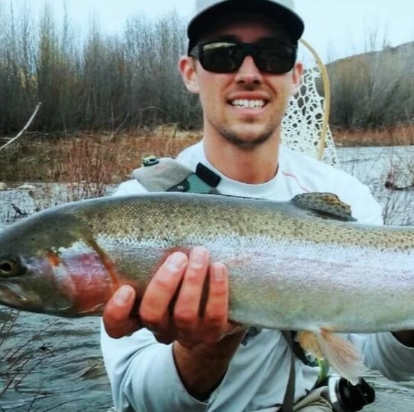 Jake Bell holding a trout, out on the water